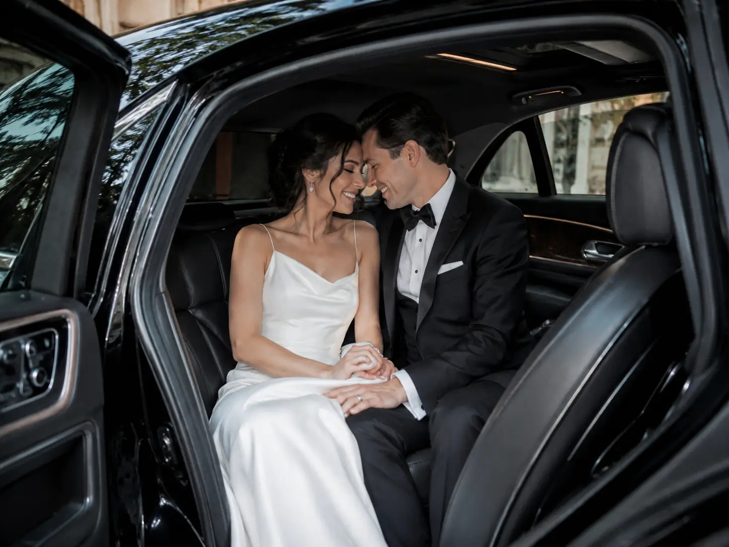 Bride and groom sitting inside a luxury chauffeur car