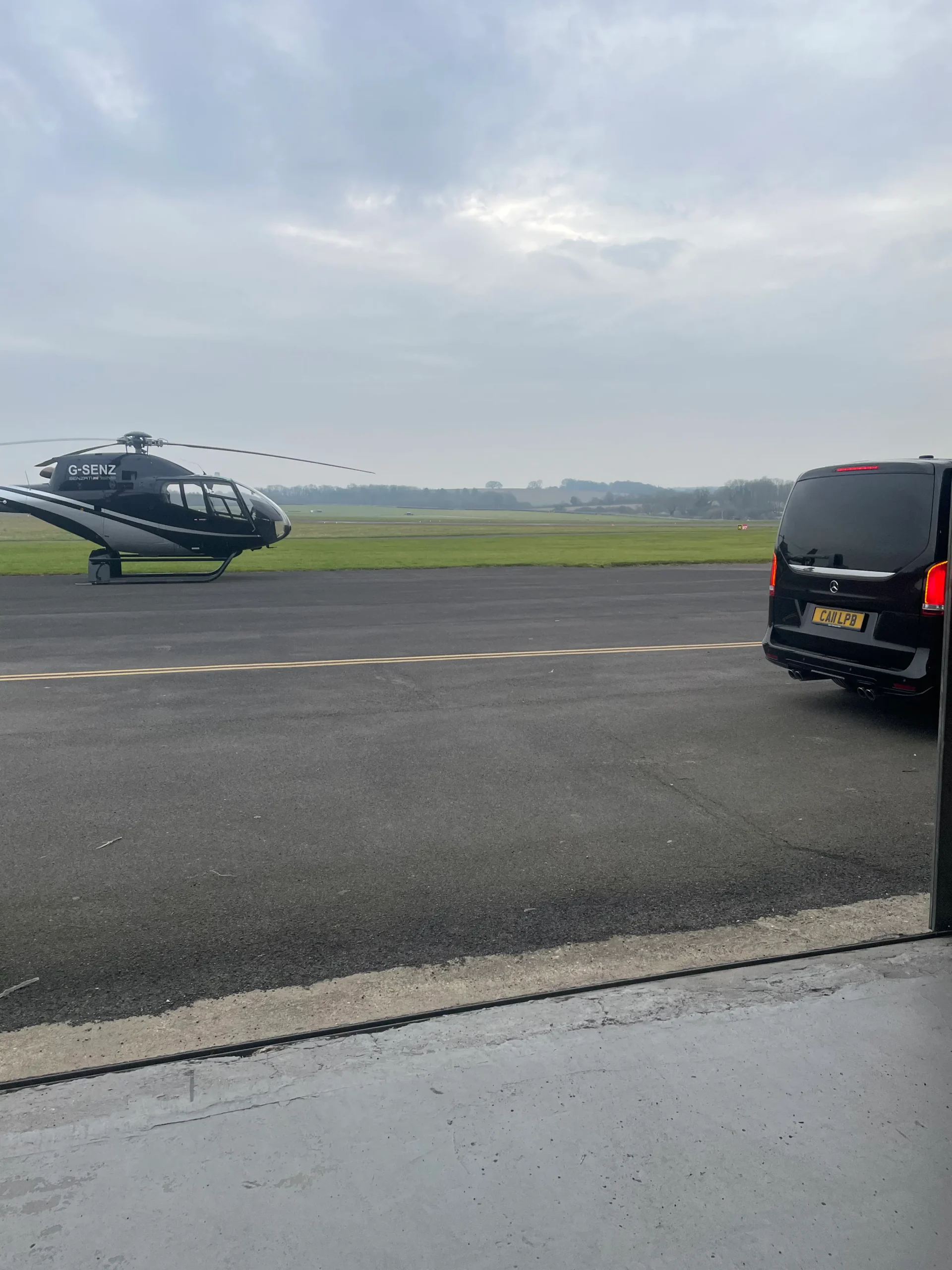 Chauffeur vehicle beside helicopter on airfield